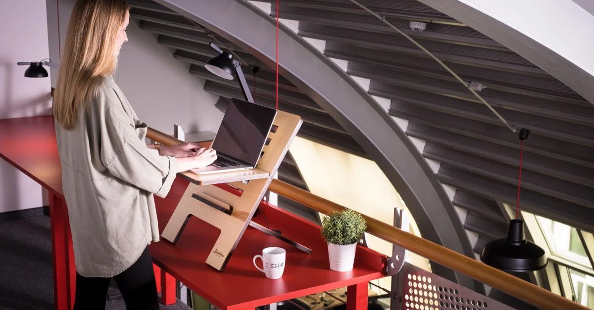 Femme utilisant un ordinateur portable sur un bureau debout à l'intérieur d'un espace de travail créatif.